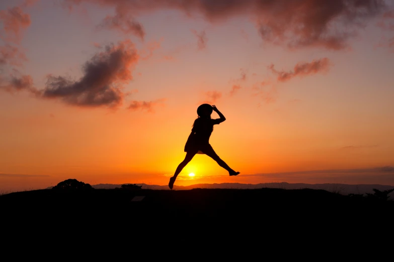 a person jumping into the air with the sun setting