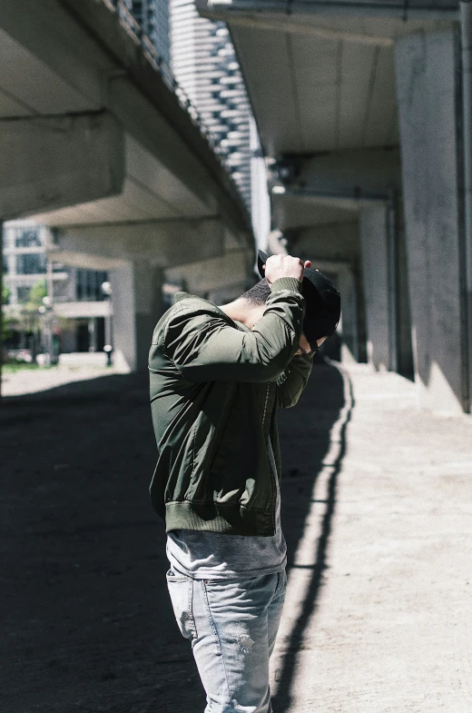 a man holding his hands up to his face in front of a large bridge