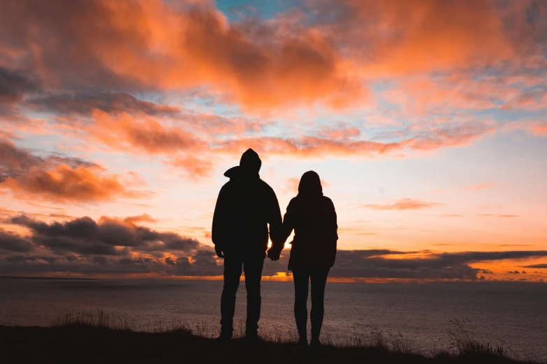 two people standing next to each other in the evening