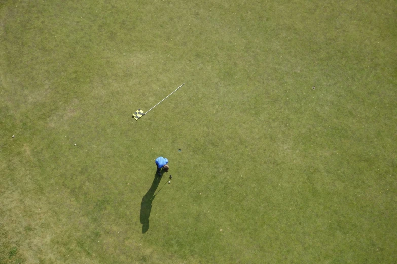 an aerial view of a person on some green grass with a kite