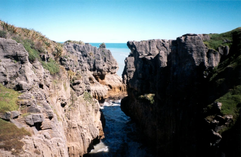 some very large rocks by the ocean on a sunny day