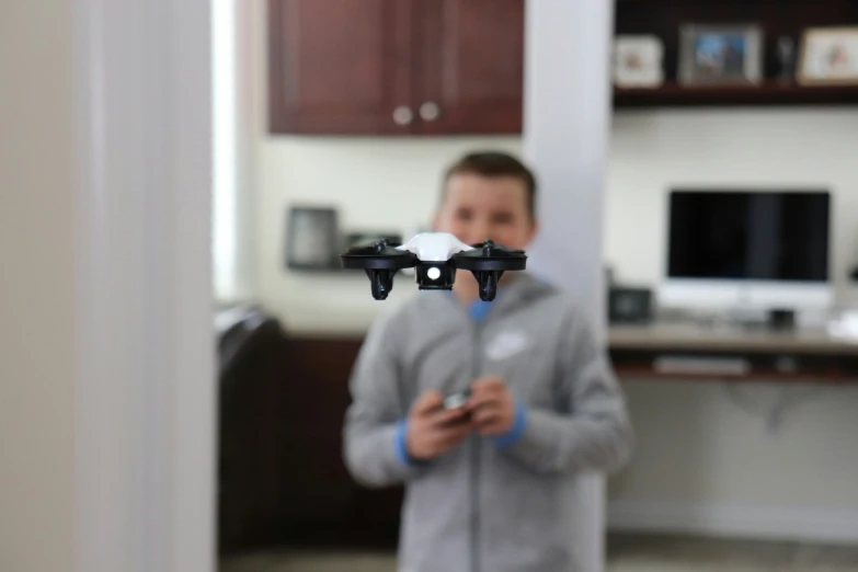 a boy in grey sweatshirt holding a remote control airplane