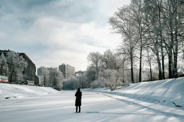 man standing alone on snow covered road near building