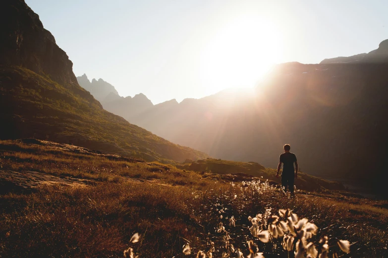 the man is standing in a grassy area with mountains