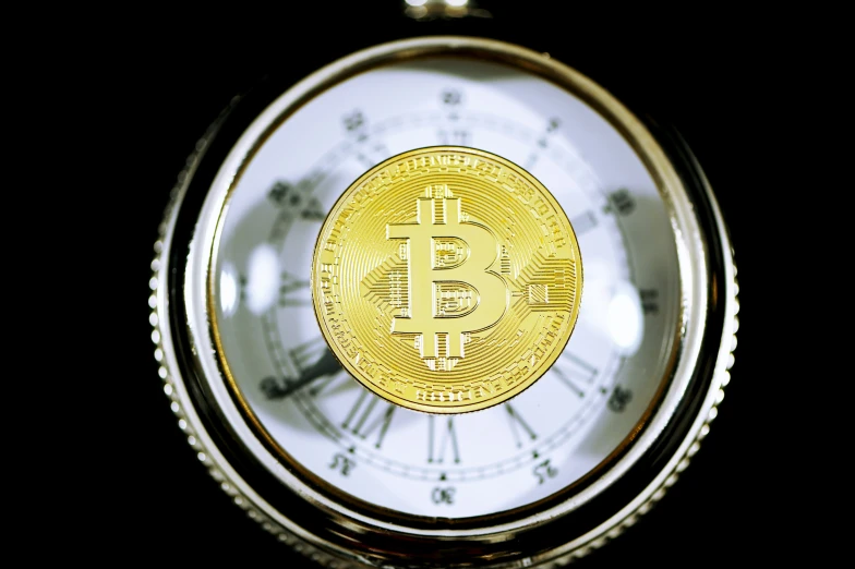 close up of a shiny gold bitcoin against a clock