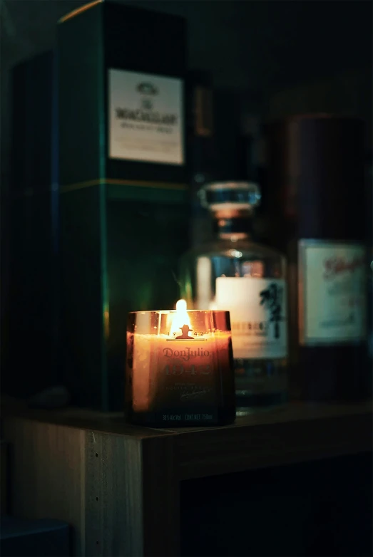 a candle sits on a table in front of several bottles