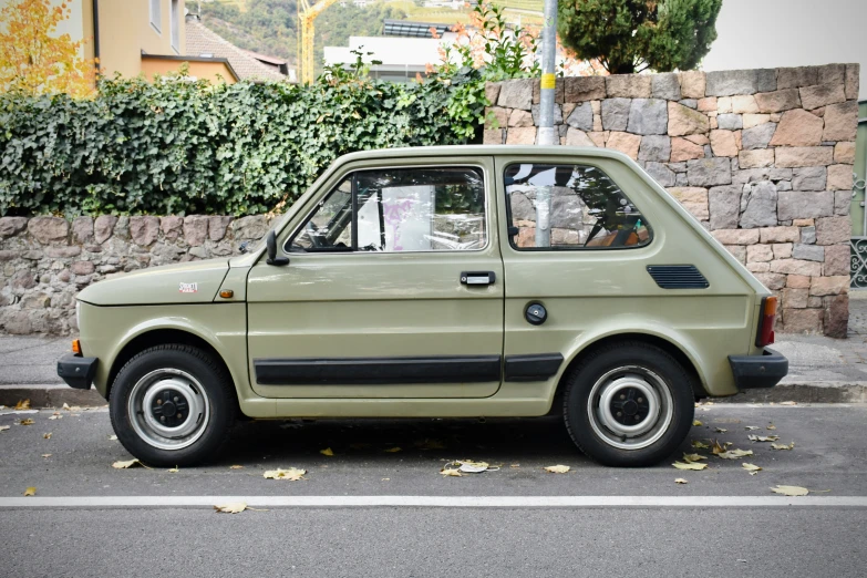 a small green car parked next to a wall