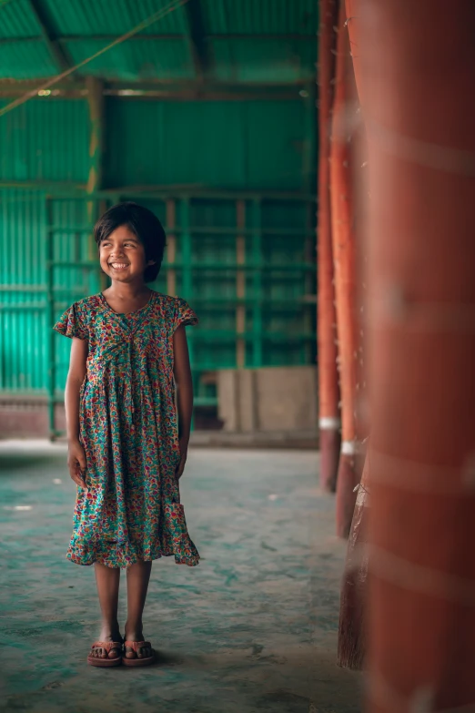 a girl in a colorful dress standing in front of a brick wall