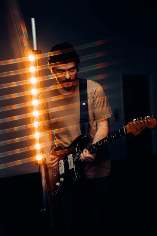 a man holding a guitar while standing next to a window