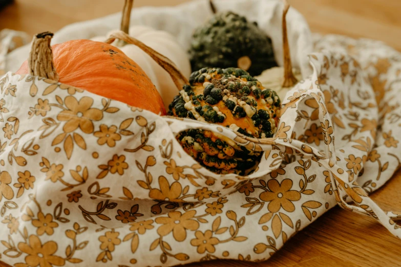 three pumpkins in a handbag on a table