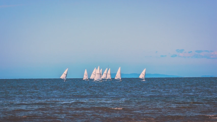 sailboats are seen sailing in the ocean during a sunny day