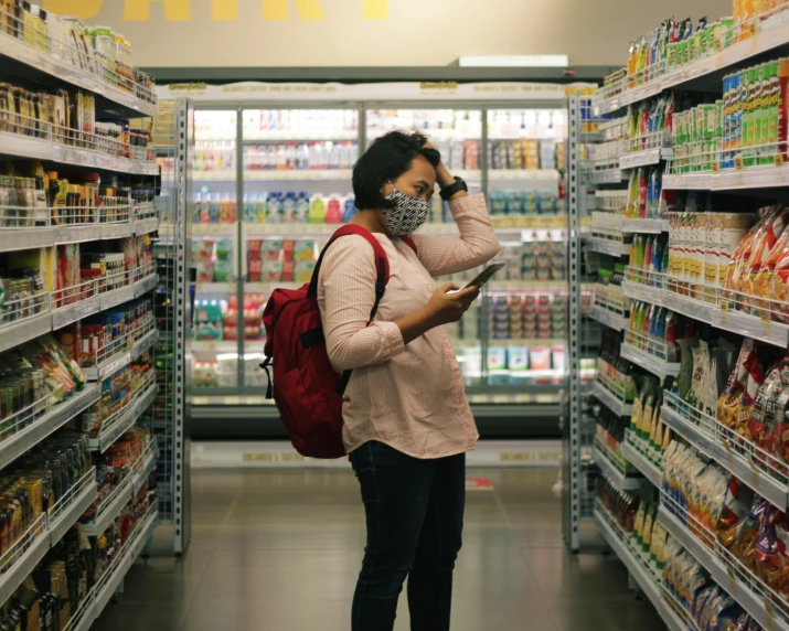 woman standing at the grocery aisle in mask looking through a labelless display