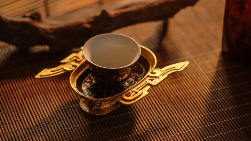 a tea cup and saucer are sitting on a place mat