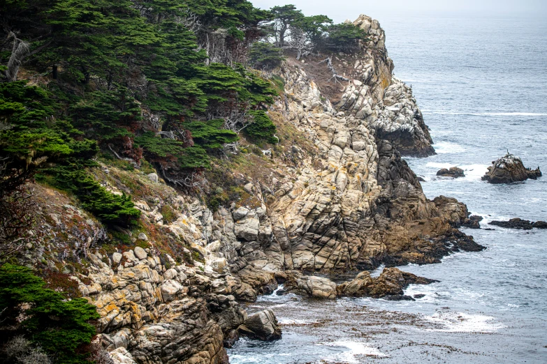 the lighthouse is surrounded by rugged rock on the shoreline