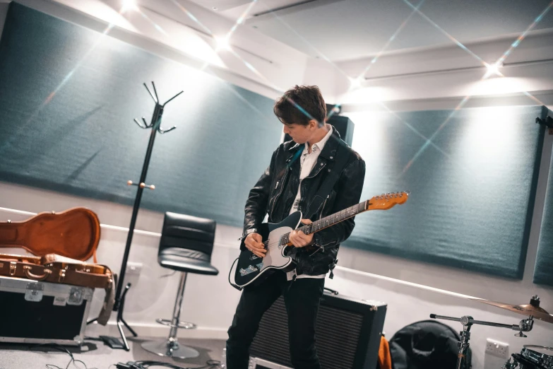 a young man playing guitar in a room with instruments