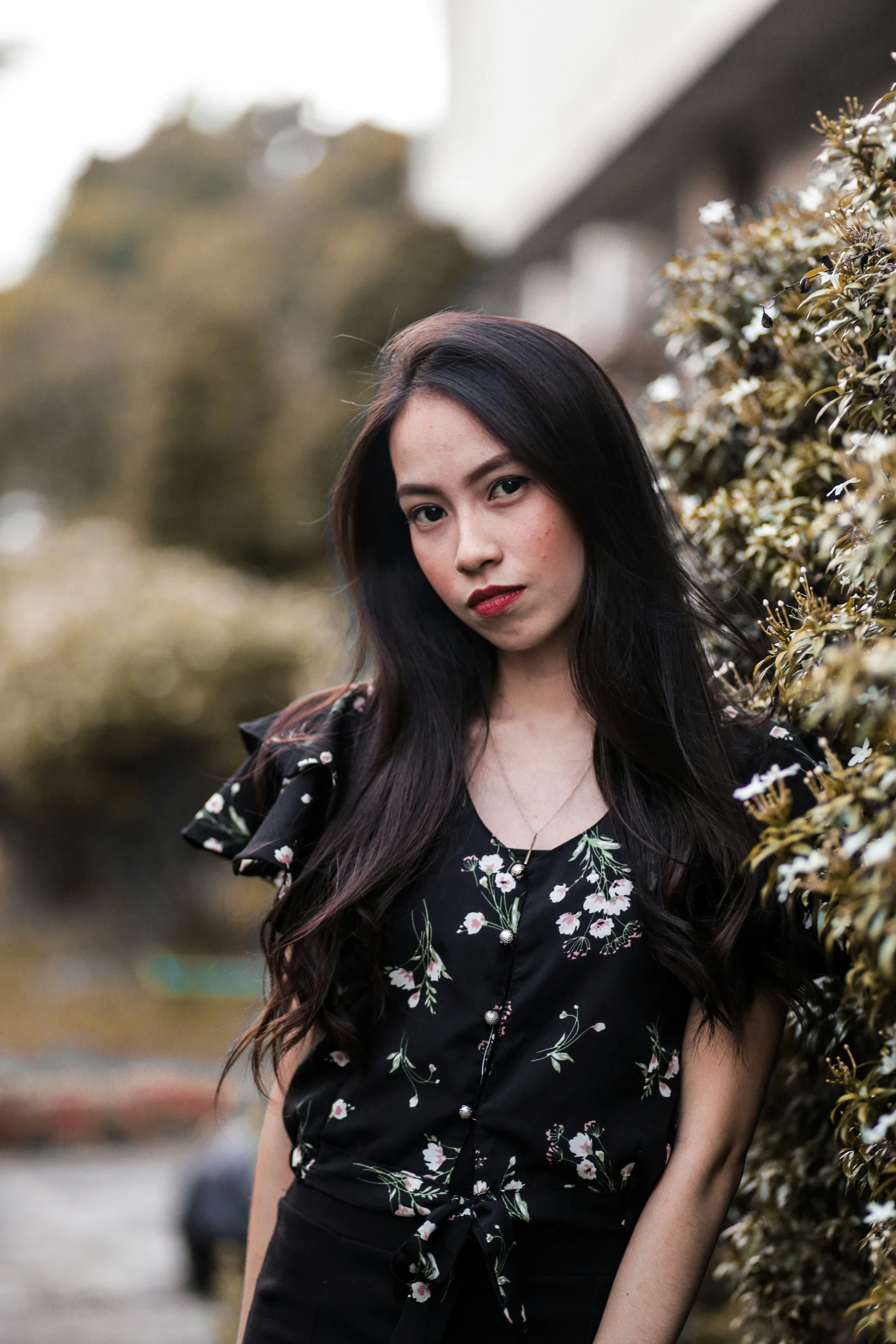 a woman standing by some bushes posing for a picture