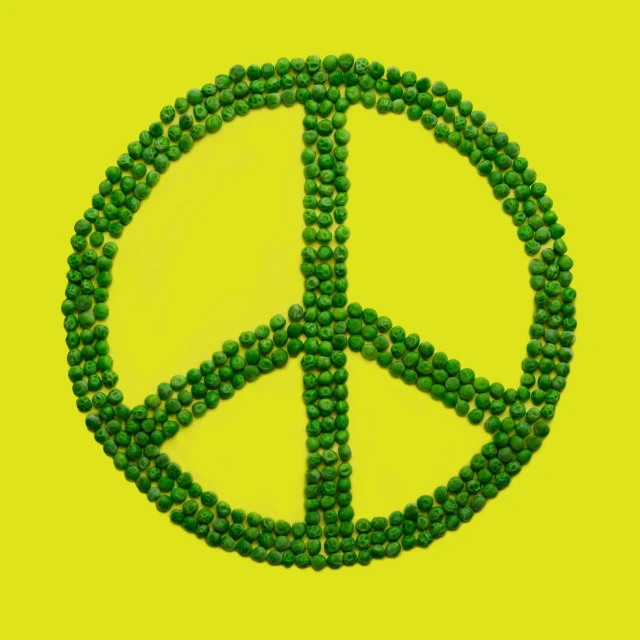 a peace sign made out of beads sitting on a yellow background