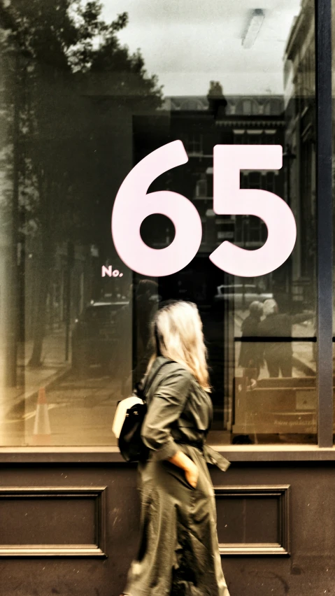 a woman walking on the side of the road by a storefront window