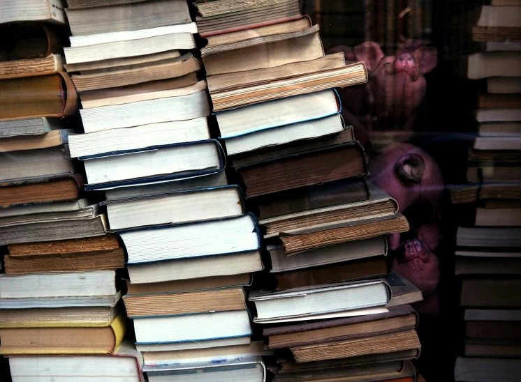 stacks of books stacked in front of a window