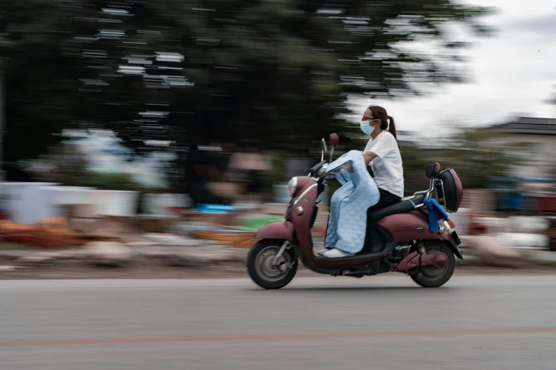 a woman on a red motorcycle driving down the street