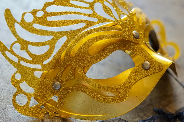 a golden mask on a surface, with beads around it