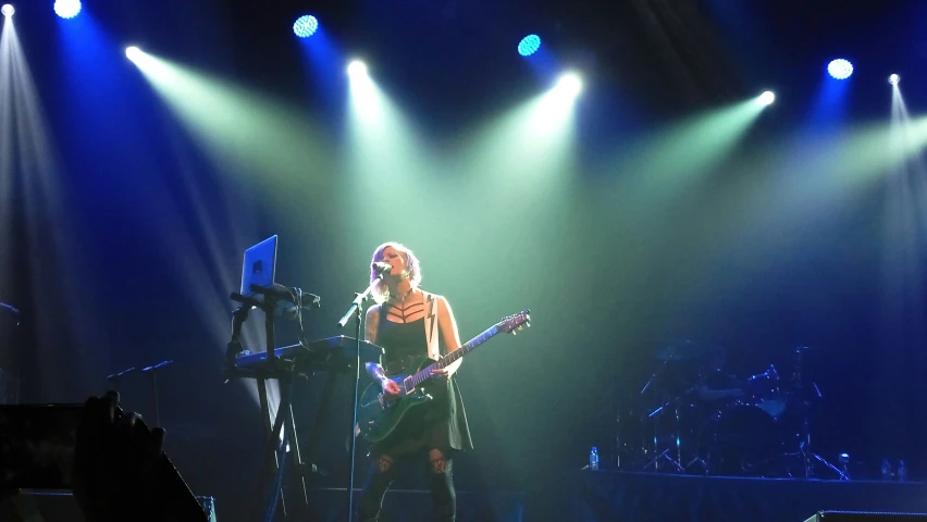 woman on stage with two guitars and three blue lights