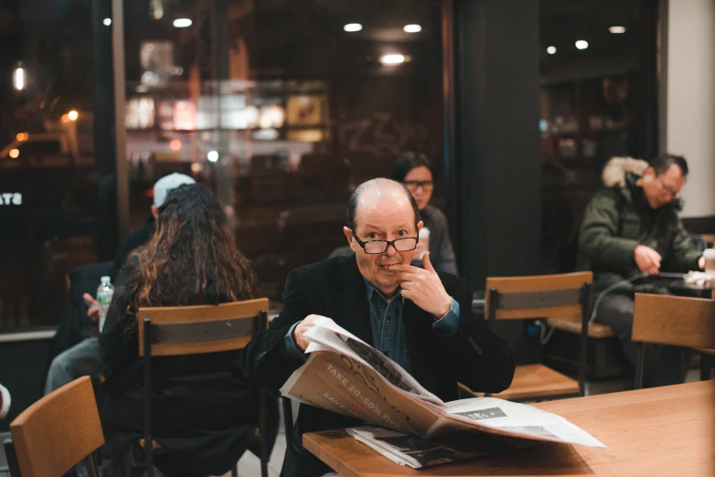 people sitting at a table looking at newspapers