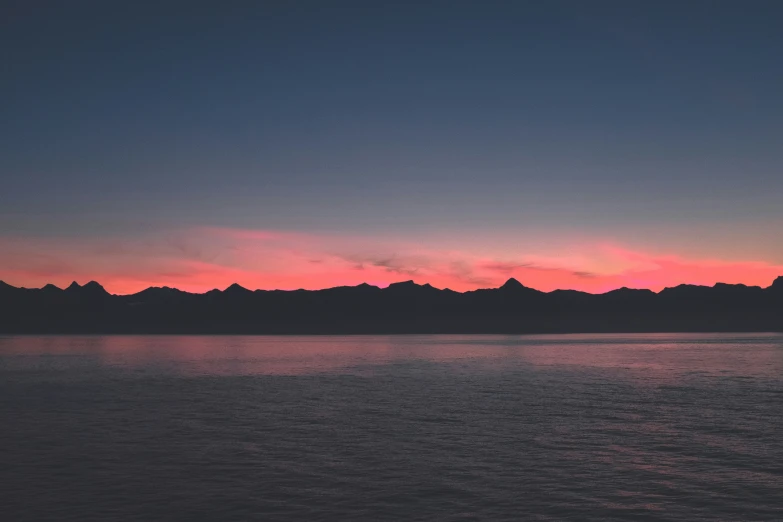 the sky is dark with little clouds and mountains