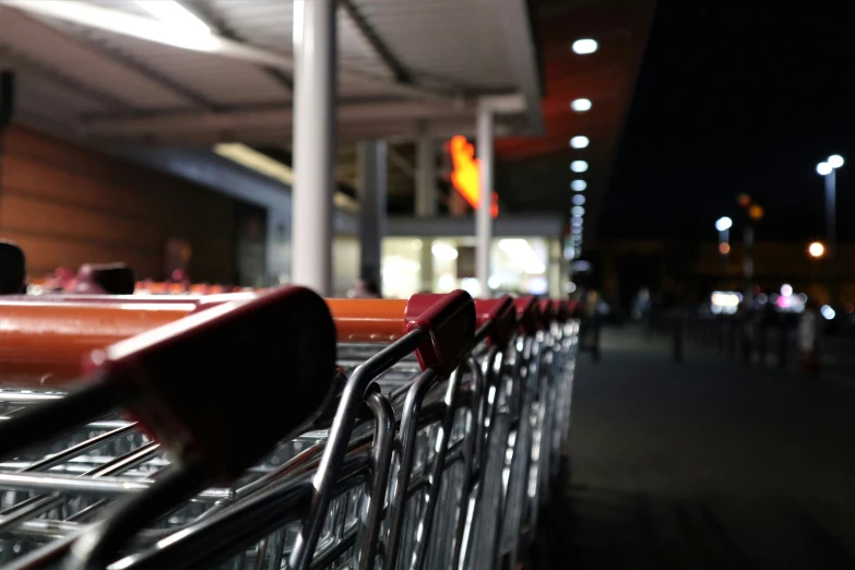 a row of empty shopping carts in front of a store at night