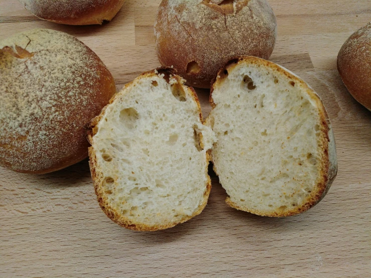 there are some white breads on a wooden table