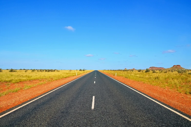 a road in the middle of a field next to a dry grass field