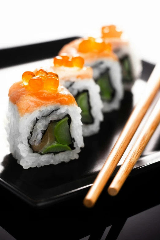 sushi on a black square plate with chopsticks