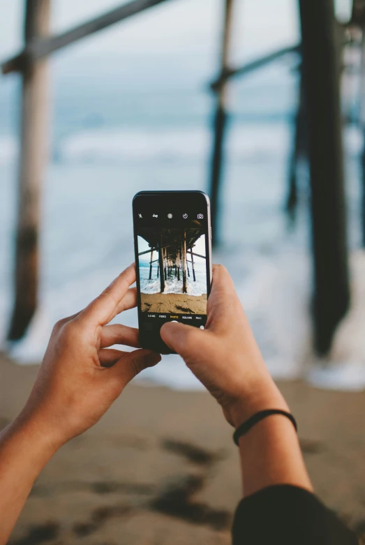 a person taking a picture of a beach and the ocean