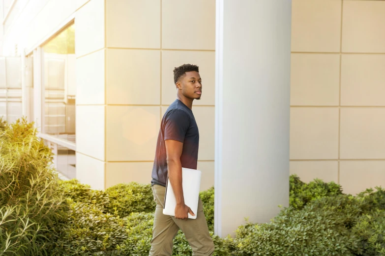 a young man holding his laptop while walking outside