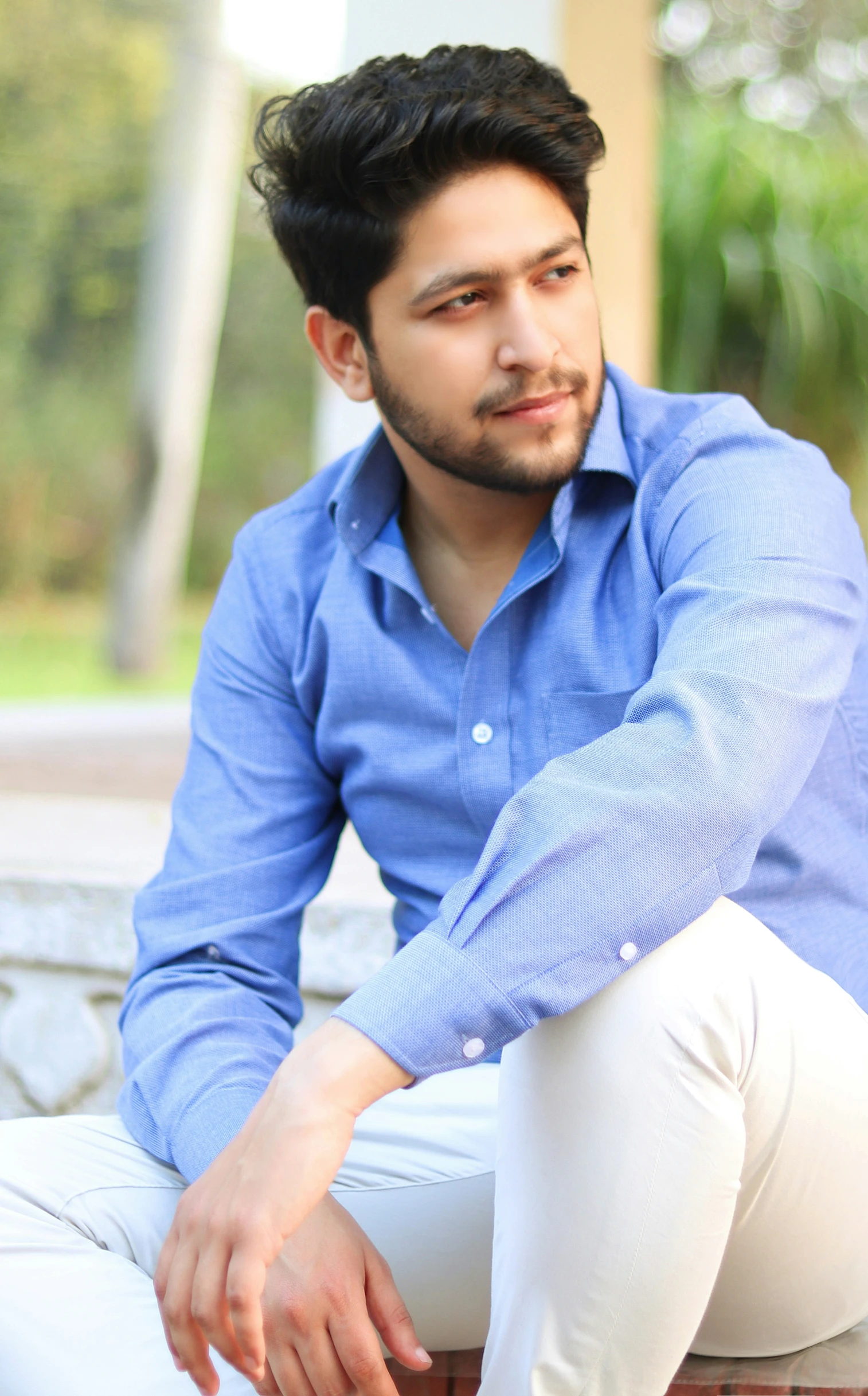 an indian man sitting on the bench and smiling