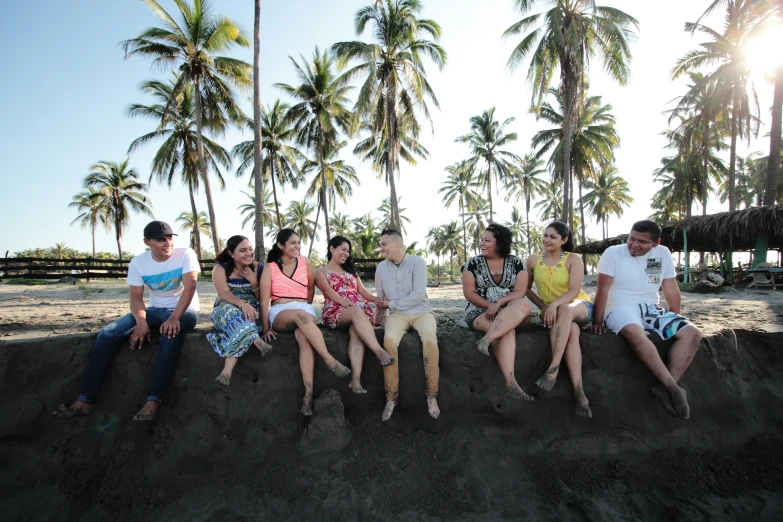 five people sit together on a mound of sand in the sun