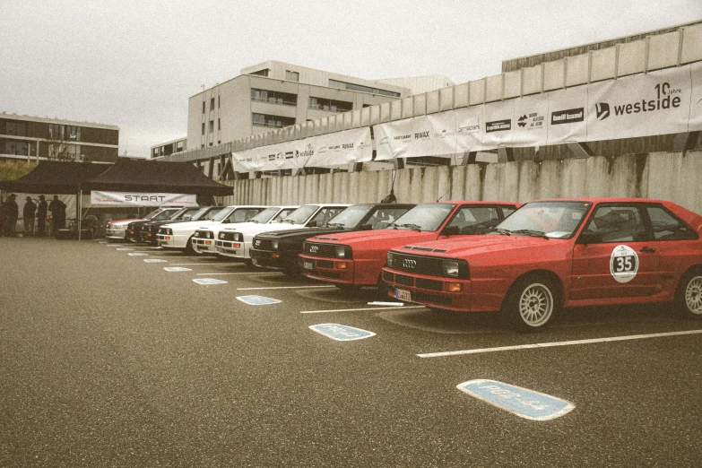 an array of small parked cars and cars waiting in the lot