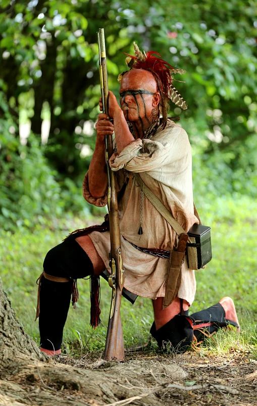 a man dressed as native american war reenacing holding a rifle and bow