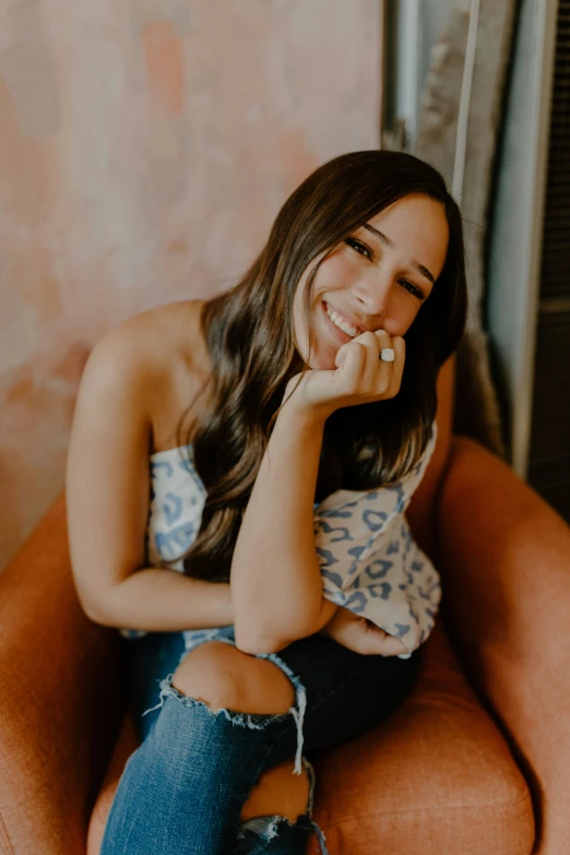 a woman is sitting on an orange chair smiling