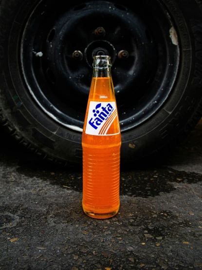 a bottle of orange soda sitting on top of a sidewalk