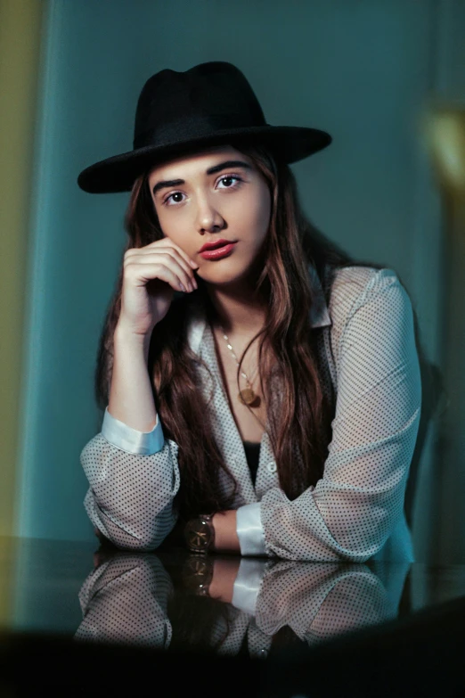 a woman wearing a hat and jacket poses in front of a green wall