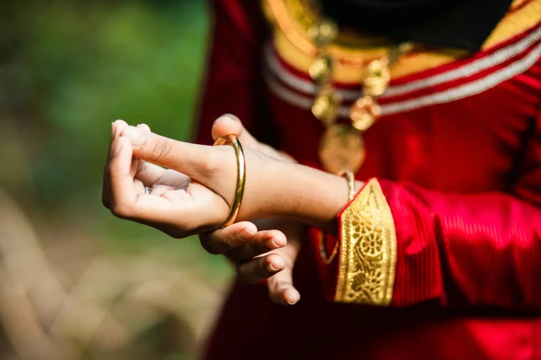 a woman holding on to a ring with gold jewelry on it