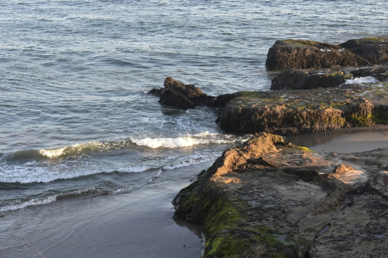 some rocks near the water and some people standing