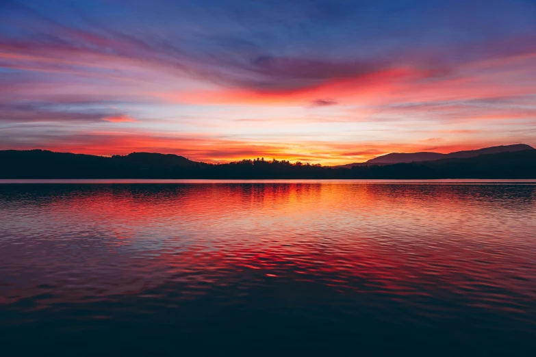 a red and blue sunset reflects off the water