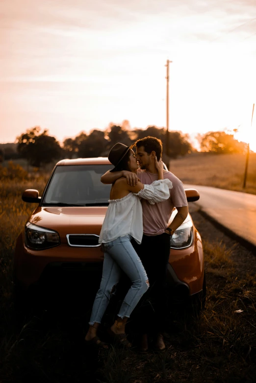 man and woman kissing in front of car on roadway