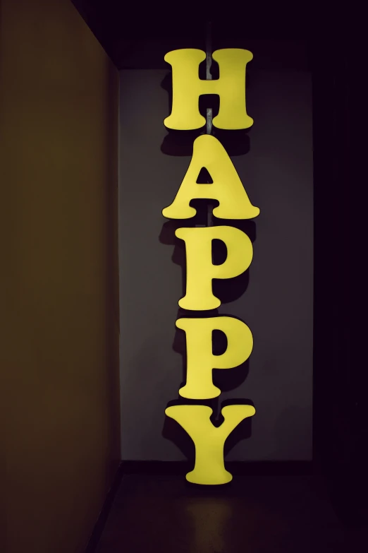 a yellow happy word is lit up on the wall