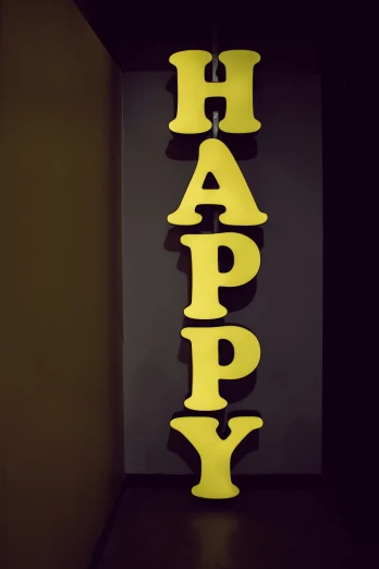 a yellow happy word is lit up on the wall