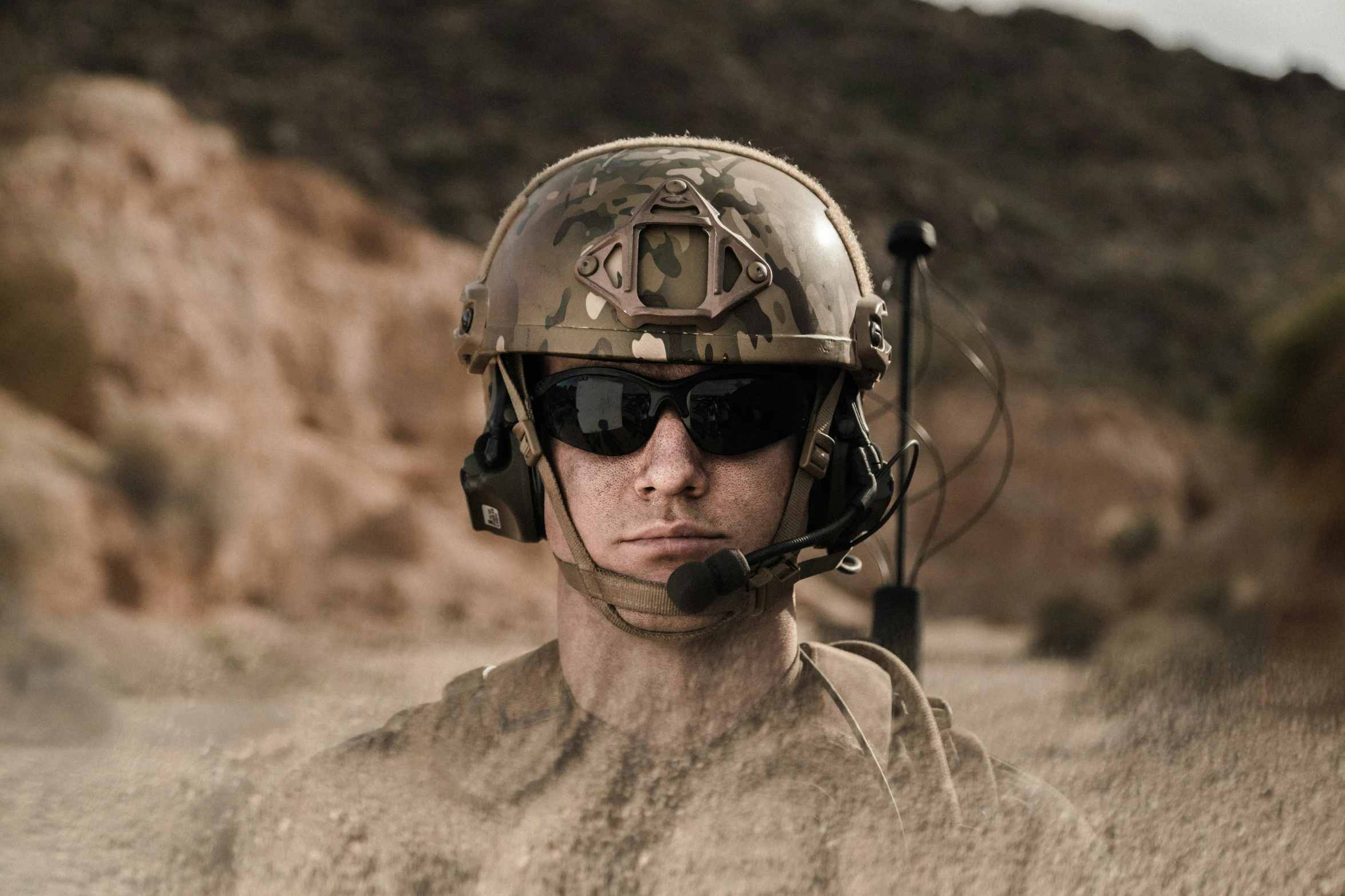 a man with sunglasses and a uniform stands in the middle of a dirt field