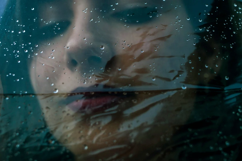 a woman's face reflected in a wet window