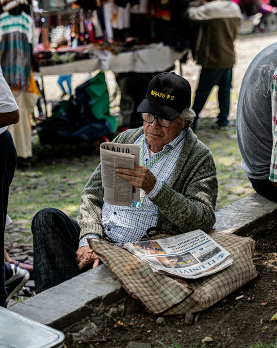 a person sitting on a park bench while reading a newspaper